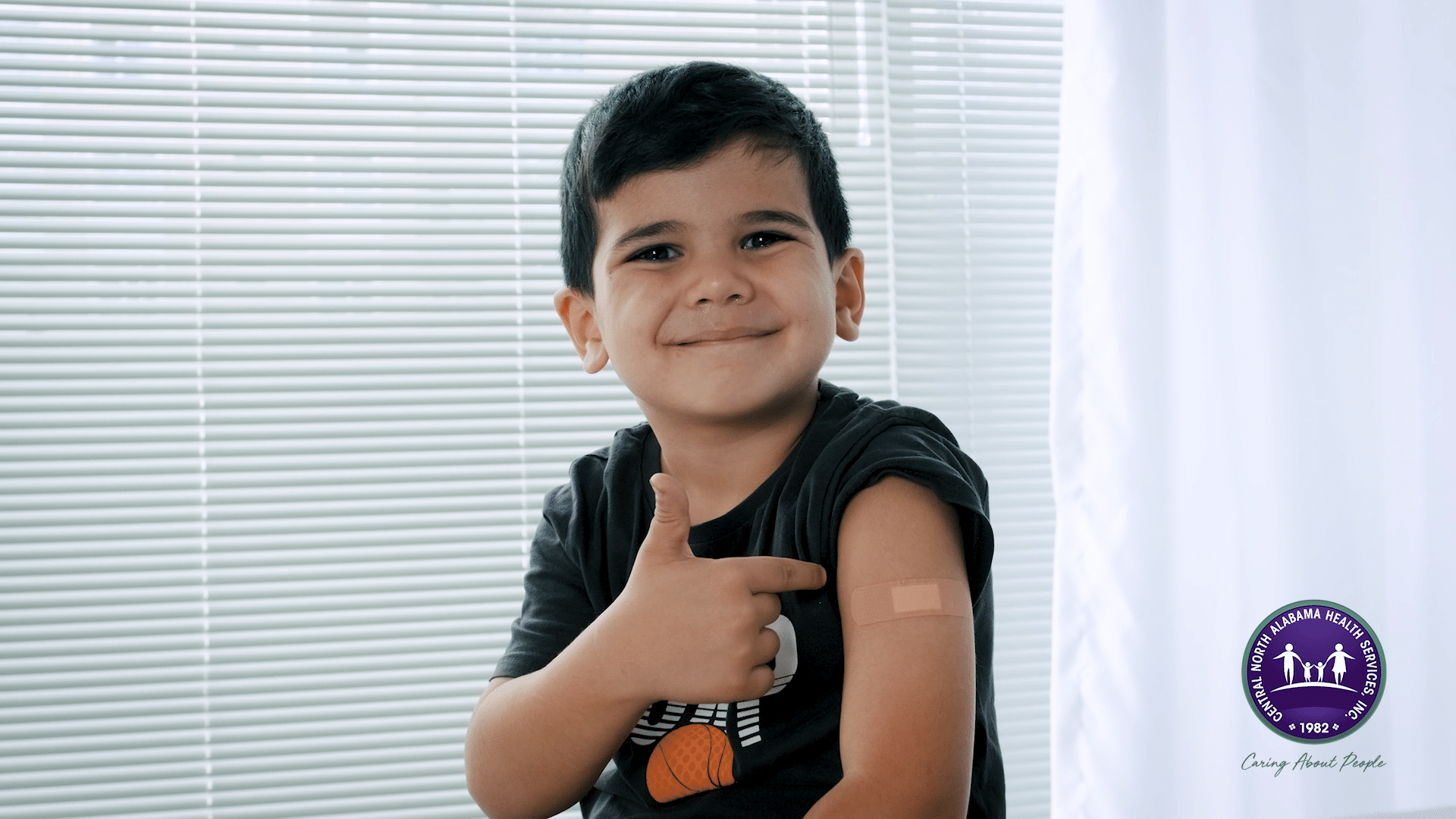 Child smiling in Huntsville, AL clinic after getting his vaccine for back to school.