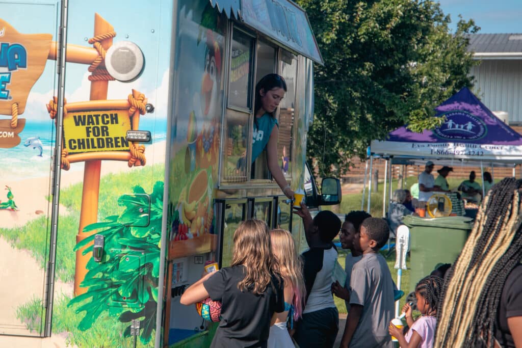 Group of kids surround the shaved ice truck during the Community Fun & Wellness Block Party in Huntsville.
