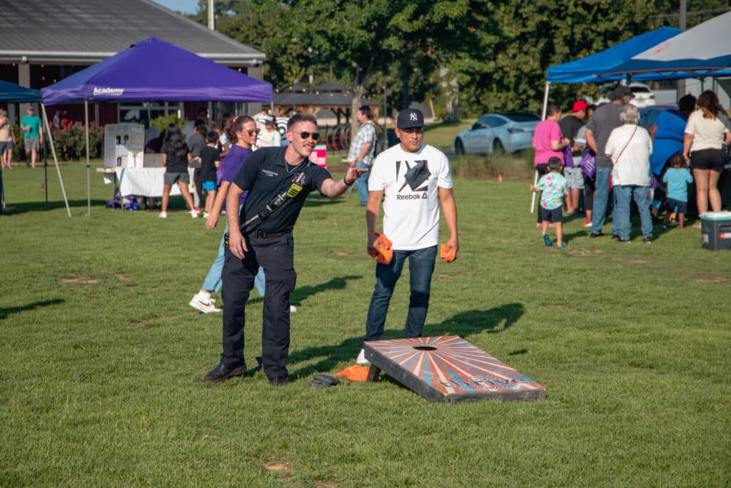 Huntsville Police officer throws bean bag, playing next to a community member.