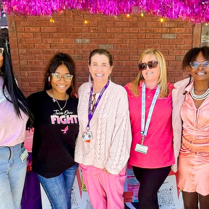 Dr. Cox in pink surrounded by other women at a breast cancer awareness event.